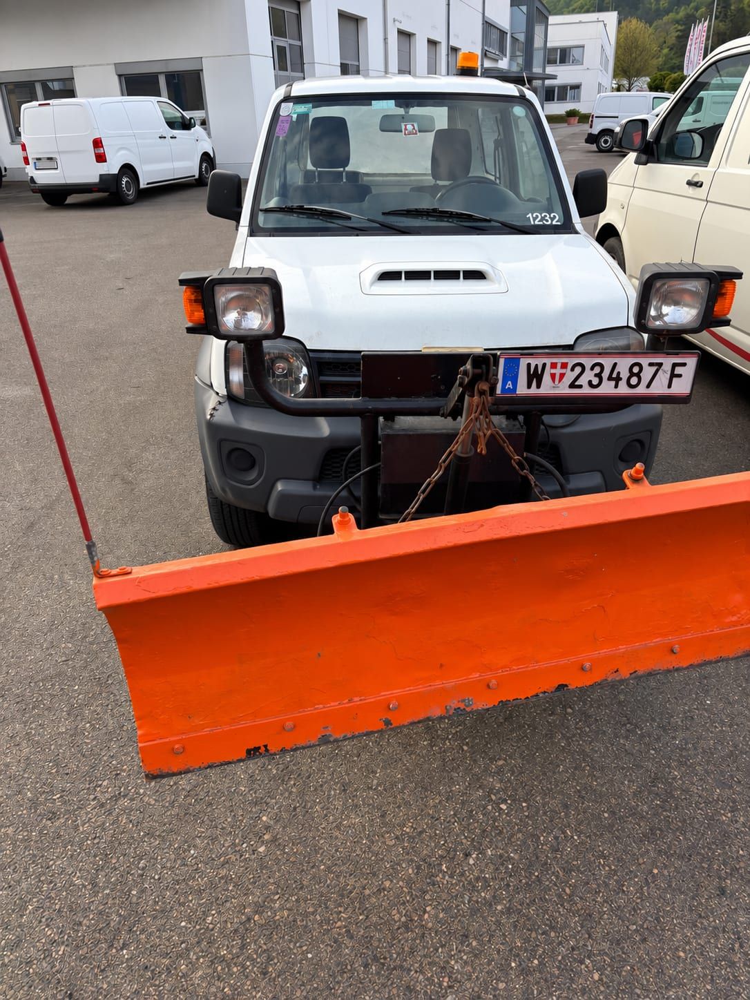 Weißer Geländewagen mit orangem Schneepflug und Rundumleuchte.